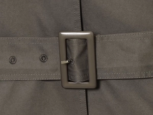Detail of taupe twill trench coat fabric featuring a matching rectangular belt buckle