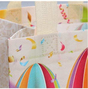 Detail of reinforced cross-stitched handles on a colorful balloon print non-woven bag