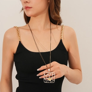 Détail du collier à double chaîne avec pendentif géométrique mat et accents dorés