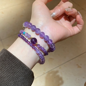 Close-up of triple-layered natural amethyst bead bracelets on wrist with golden accents