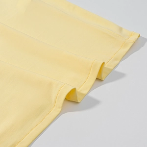 Close-up of vibrant yellow knitted fabric with fine double-needle stitching detail