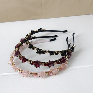 Detailed macro view of handmade pink, burgundy, and black crystal headbands in gold metal settings