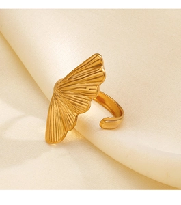 Macro shot of golden ginkgo leaf ring with polished radial texture on silky fabric