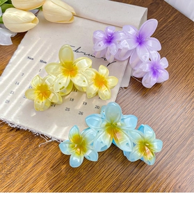 Detailed view of colorful floral hair claws in purple yellow and blue on a wooden desk