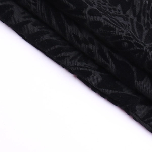 Détail du tissu en velours noir floqué avec motifs en maille complexes et textures en relief