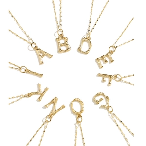Colliers alphabet en acier inoxydable doré 316L avec texture bambou sur fond blanc