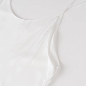 Dettaglio macro dell'abito sottoveste in raso bianco con tessuto setoso e spalline fini