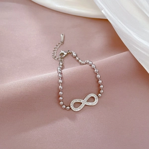 Macro view of silver infinity charm bracelet with polished beads and lobster clasp