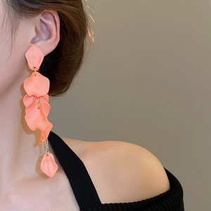 Close-up of elegant orange-pink rose petal tassel earrings worn by a model