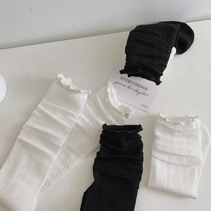Detailed flat lay of black and white lace mesh socks with frill trim and textured knit