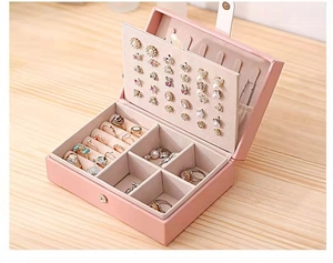 Pink jewelry box detail with dedicated earring plate and ring slots for organization