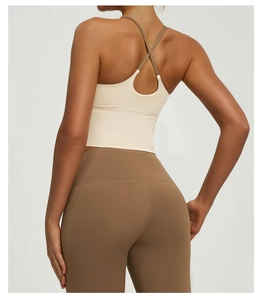 Detail der gekreuzten Träger am beigen Yoga-Top und braunen Leggings mit hoher Taille