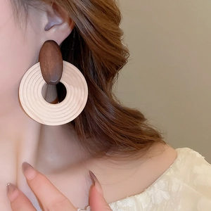 Macro detail of geometric wooden drop earrings featuring natural wood grain on a model