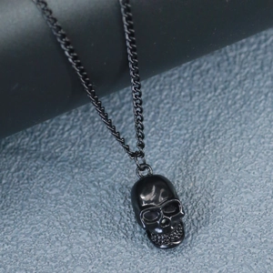 Detail shot of black skull pendant with curb chain against a textured grey background