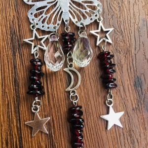 Close-up of silver butterfly suncatcher with crystal drops and crescent moon on wood background