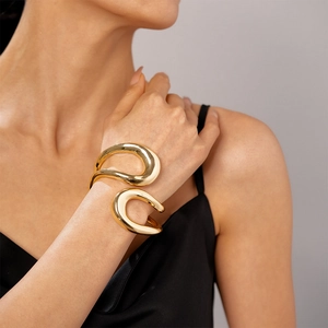 Close-up of a sculptural gold irregular double-ring bangle worn on a model's wrist