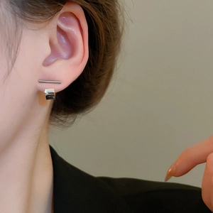 Macro view of minimalist silver geometric earrings worn by model for an elegant look