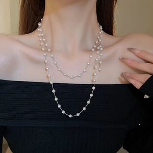 Gros plan d'un collier double rang de perles fantaisie porté sur mannequin avec chaîne argentée