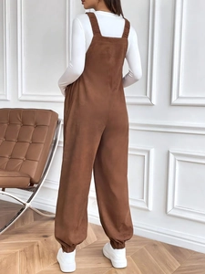 Detail of adjustable waist on brown corduroy maternity overalls from a back side view