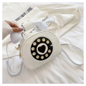 Close-up of white patent leather crossbody bag with vintage telephone dial and heart design