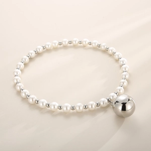 Detail shot of white round pearls with small silver beads and a large hollow metal ball