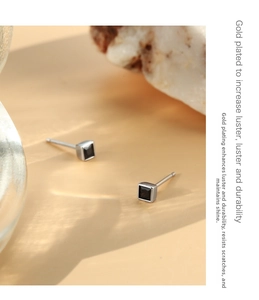 Macro shot of black square zircon stud earring with silver metal base on stone