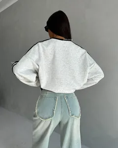 Detail of grey crewneck sweatshirt with shoulder stripes and frayed denim jeans back