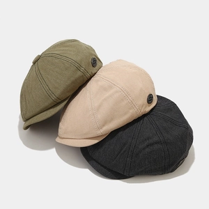 Detailed side view of vintage newsboy caps showing cotton twill texture and metal button decor