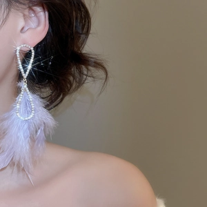 Nahaufnahme eleganter lila Feder-Ohrringe mit glitzerndem Diamantbesatz