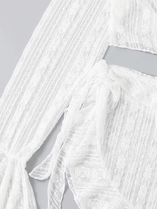 Detail of white crochet lace beachwear featuring hollow-out floral patterns and tie-up design