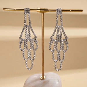 Detailed view of silver fan-shaped tassel earrings with rhinestones on a display stand