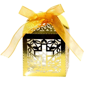Macro shot of gold laser-cut cross candy box with shiny metallic finish and ribbon bow