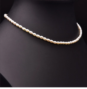 Macro shot of natural white baroque seed pearls on an 18k gold plated choker chain