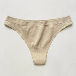 Detailed close-up of beige seamless thong featuring elastic fabric and printed logo