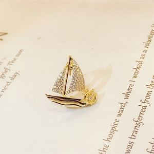 Elegant gold sailboat brooch with clear crystals and black enamel on vintage book pages