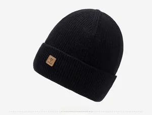 Detail view of black knit beanie with a brown leather logo patch and soft thermal texture