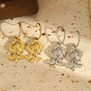 Elegant rose flower drop earrings in gold and silver finish on natural stone background