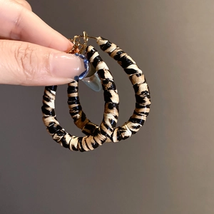 Close-up of leopard pattern acrylic C-shaped earrings with woven texture and gold needle