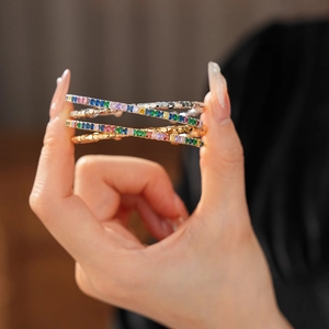 Detailed macro view of stacked gold and silver bracelets with multicolored zircon stones