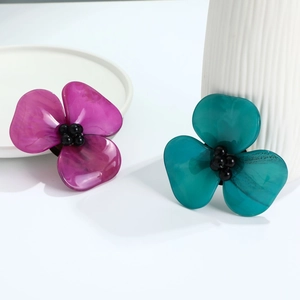 Detailed macro view of purple and teal resin flower brooches with black bead centers