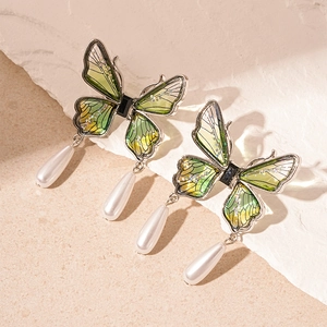 Detail of green butterfly earring with silver metallic frame and white drop pearls