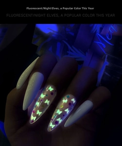 Luminous stiletto nail art showing glow-in-the-dark butterfly sequins in dark setting