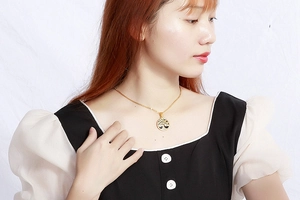 Close-up of golden Tree of Life circular pendant on necklace worn by a model