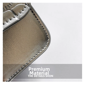 Macro detail of glossy metallic leather with fine stitching on a mini crossbody bag