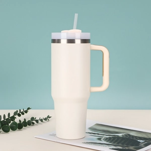 Detail of a beige 40oz stainless steel tumbler with handle and straw in a lifestyle setting
