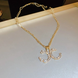 Detail of gold double-C pendant with micro pearls and crystals on layered chain