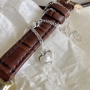 Detailed view of a silver heart-shaped pendant necklace with a white pearl inlay