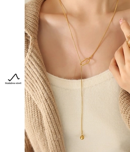 Detailed view of long Y-style stainless steel gold necklace worn on a knit cardigan
