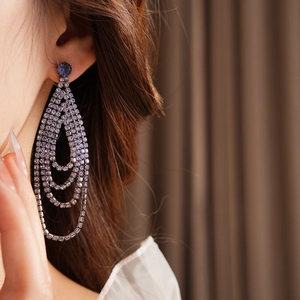 Close-up of model wearing geometric purple tassel earrings with sparkling rhinestones