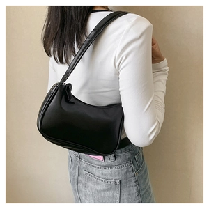 Close-up of a minimalist black hobo shoulder bag with smooth faux leather on a model